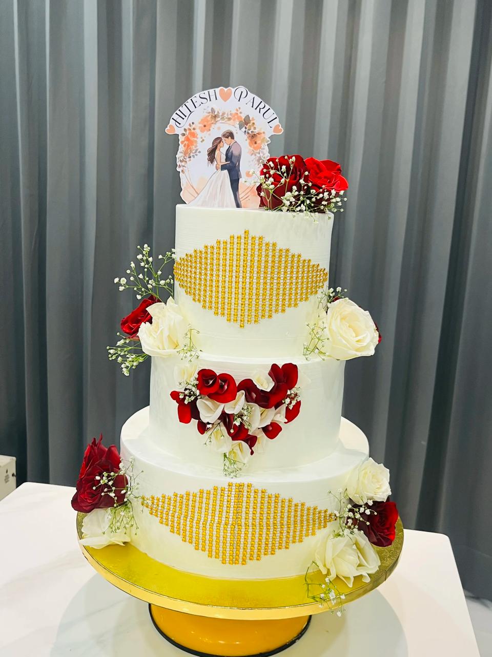 Three-tier white wedding cake decorated with red and ivory roses